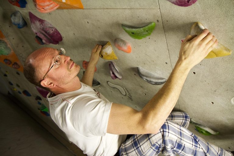 Climber reaching across an overhanging indoor bouldering wall